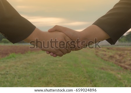Two businessmen shaking hands during a meeting in the green and sky background, success, dealing, greeting & business partner.Two businessmen shaking hands vintage tone photo