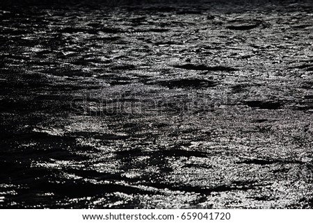 Water silver dark ripples on the river with glare and reflections from the sun. Abstract backgrounds.