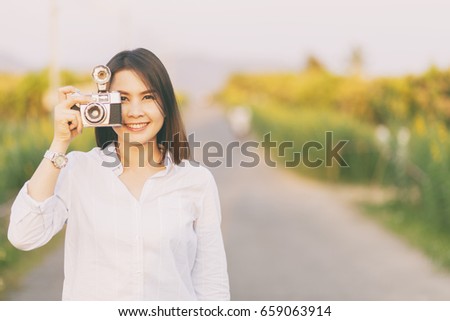 Beautiful woman hand holding a camera on field in summer