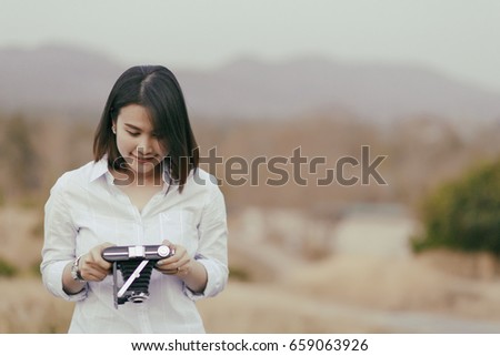 Beautiful woman hand holding a camera on field in summer