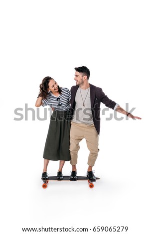 young cheerful couple riding on skateboard isolated on white