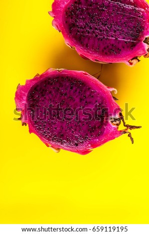 Exotic fruit dragon eyes pink with pink midway on a yellow background.
Dragon eye fruit macro picture. Two halves of dragon fruit a bright eye on striped yellow background.