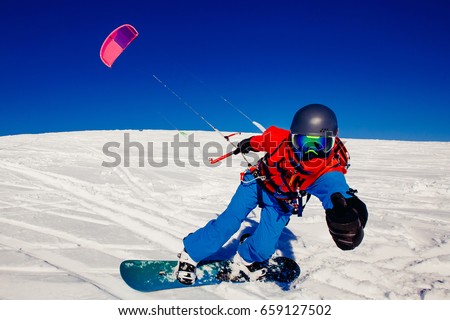 Snowboarder with kite on fresh snow in winter in tundra against clear blue sky. Concept sports snowkite. Royalty-Free Stock Photo #659127502