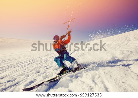 Skier with kite on fresh snow in winter in tundra against a clear blue sky. Concept sports snowkite on ski. Royalty-Free Stock Photo #659127535