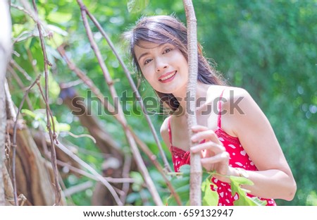 asian woman wearing red dress over on green nature background.