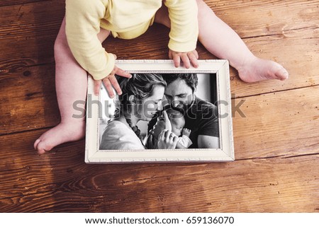 Unrecognizable baby holding family photo. Fathers day.