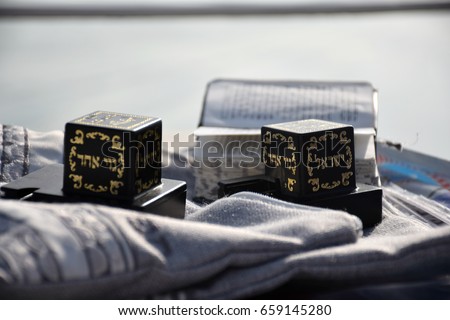 Tefillin (Judaica item using for the famous jewish prayer "Shema Israel" - hear us our lord) and the Jewish bible on a Shawl bag. Royalty-Free Stock Photo #659145280