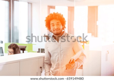 Portrait of young businessman holding laptop in office
