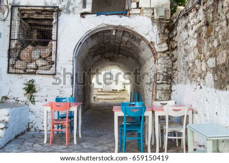 Courtyards of old town of Marmaris. Entrance to courtyard in form of an arch in  background of brick house next to table with colorful chairs in old town of Marmaris, Turkey