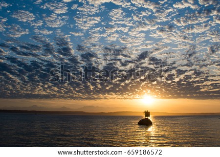 Mackerel Sky II: The mackerel clouds lit by a setting sun over the Puget Sound. Royalty-Free Stock Photo #659186572