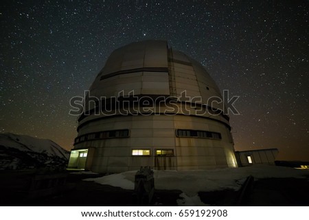 Night view. A special astrophysical observatory against the background of the starry sky and snowy peaks of the Arkhyz mountains.
