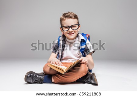 Little boy with backpack reading book in yoga pose