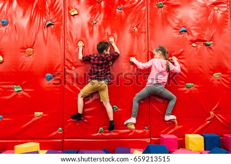 Kids climbing on a wall in attraction playground Royalty-Free Stock Photo #659213515