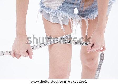 Close up of female hands using measuring tape measuring her legs size (healthy and weight loss or diet concept)