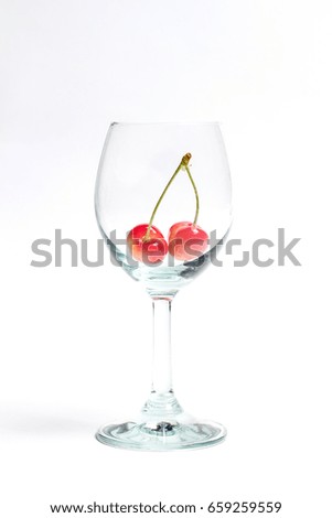Two cherries in a wine glass on a white background