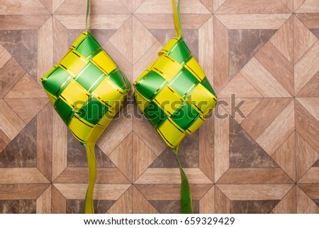 Ketupat decoration on wooden wall. Ketupat is traditional food in Malaysia during the Hari Raya celebration. It is made of palm leaves and a little rice included.