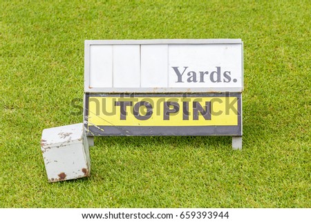 Close-up white wooden tee off area or tee box with length information sign in background.