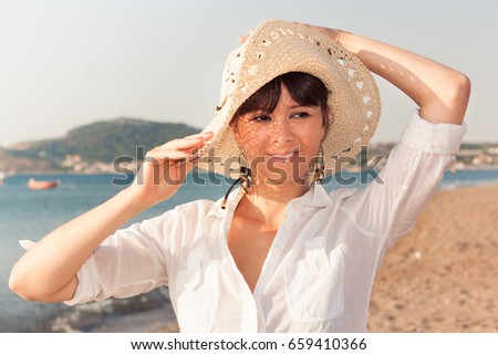 Portrait of a young female with straw hat at the beach