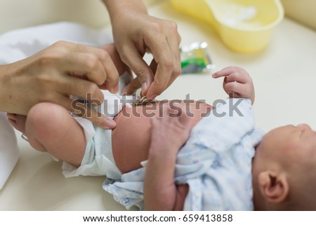 Mother is cleaning the navel of a newborn baby. Royalty-Free Stock Photo #659413858