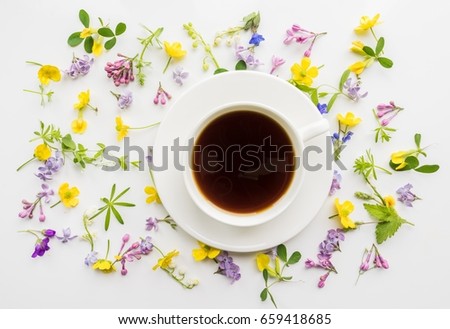 Cup of black coffee on the background of small flowers and leaves. Cute simple background. Floral backdrop for banners, cards, covers. The theme of the beginning of the day, summer, spring. 