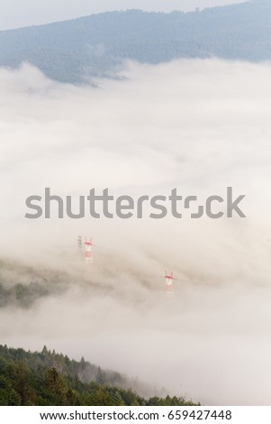 Heavy fog dissolving showing power line poles in Polish Beskid