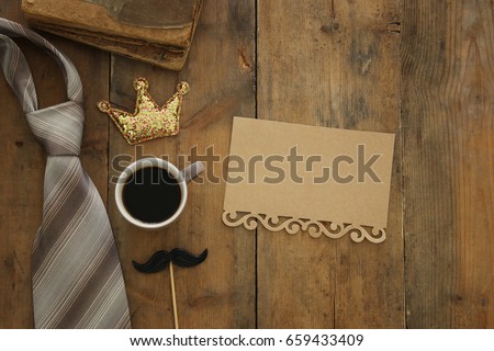 top view image of old books, glitter crown, necktie and cup of coffee. Father's day concept
