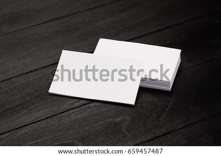 Blank corporate identity business card and stack on black stylish wood background with blur, template.