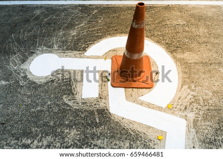 Wheelchair sign at outdoor and traffic cone overlap the symbol.