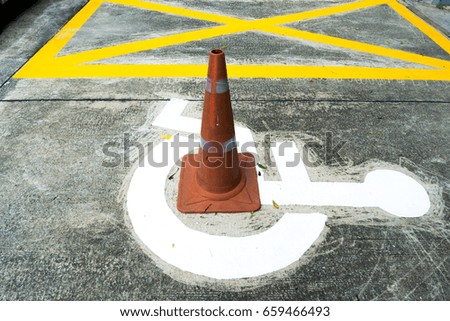Yellow line disable parking Wheelchair sign at outdoor and traffic cone overlap the symbol.
