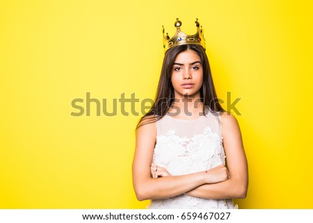 Beautiful young woman wearing crown and nice dress on yellow