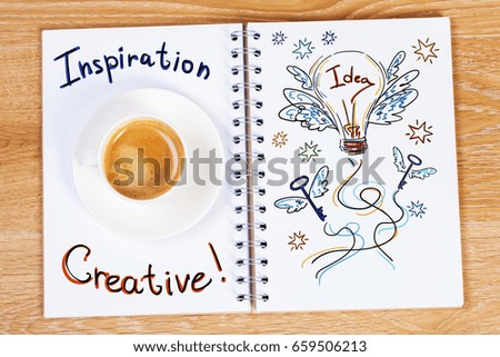 Top view of wooden desktop with lamp drawing in open spiral notepad and coffee cup. Creative concept