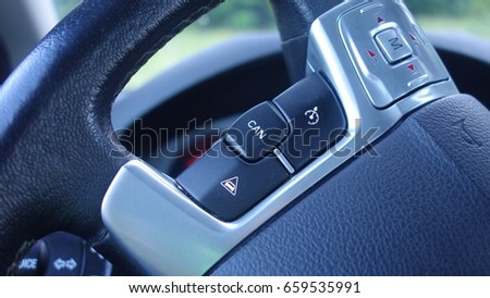 Adaptive cruise control buttons - on and off command, adjustable distance between cars, volume up and down command, leather steering wheel, inside car partial dashboard, chrome ornaments. Royalty-Free Stock Photo #659535991