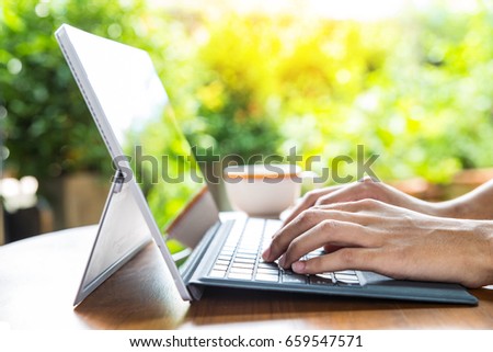Hands of  Teenager boy touching  laptop keyboard on wooden desk with cup of coffee in the background at home , selective focus Royalty-Free Stock Photo #659547571