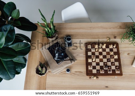 Creative workplace concept with old retro cameras lying on books and chess board during the game