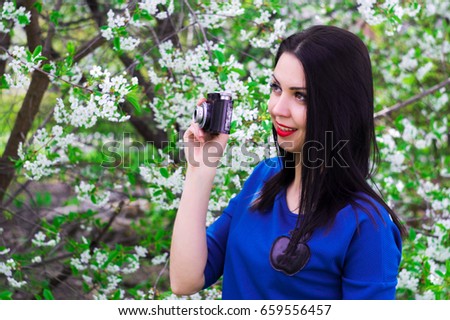 A young woman with retro camera photographing blooming in spring park