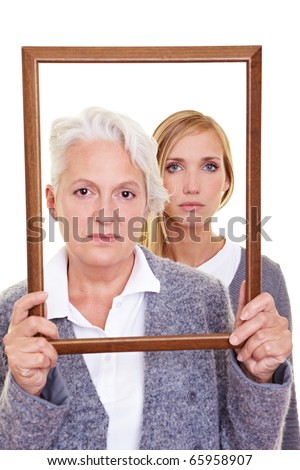 Grandmother and granddaughter looking seriously through an empty frame