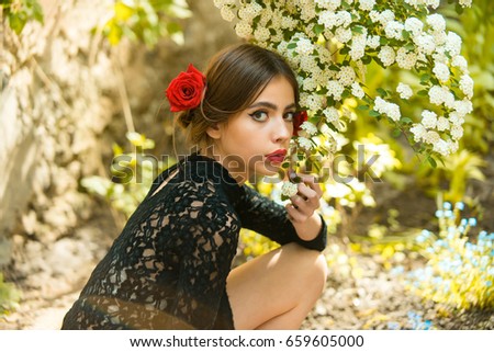 young spanish girl in spring garden with red lips and rose in hair