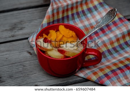 Breakfast concept: porridge of oatmeal and fruit. In a red circle. On a wooden table