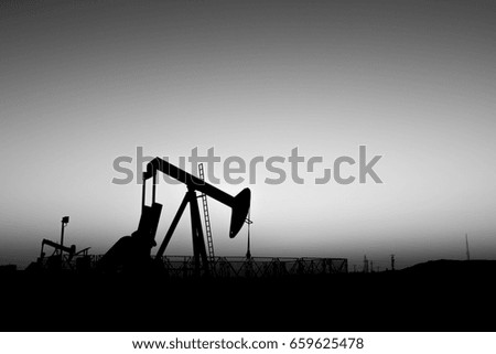 Silhouette of crude oil BPU pump in oilfield at sunset blue hour   