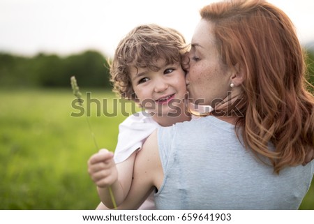 A Cute kid boy with his mother on a summer meadow