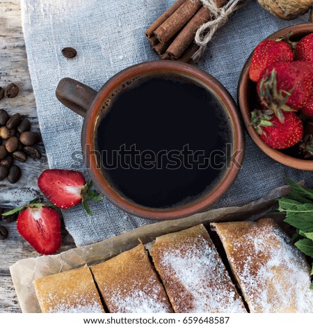 A cup of espresso on a wooden background. Coffee beans, strawberries. Breakfast, coffee on the nature.