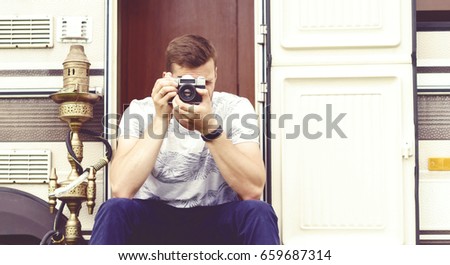 Young, handsome hipster taking pictures outdoors at summer. Holiday, journey, vacation concept.