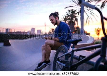 Portrait of a young business man using mobile phone while hanging out in the skate park.