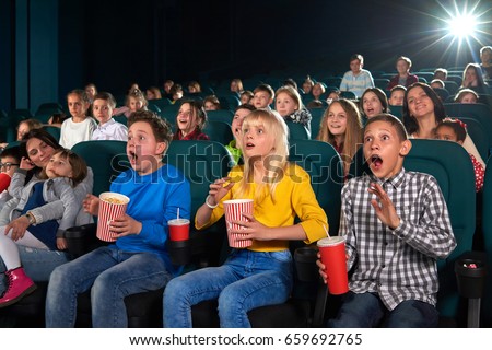 Young boys and girls looking shocked and surprised watching a movie at the cinema emotions expression shock surprise unexpected action activity entertainment people leisure hobby lifestyle concept.