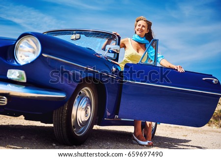 Beautiful happy woman sitting in retro cabriolet car