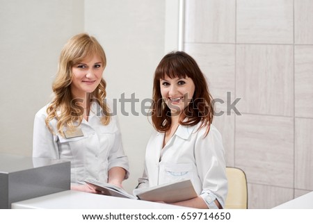Two female doctors working together at the hospital. Nurses filling medical documents at the clinic profession occupation colleagues writing assistance medical industry healthcare concept.