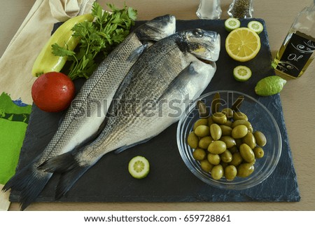 Two ready to cook raw fish with vegetables on stone slate board. Top view