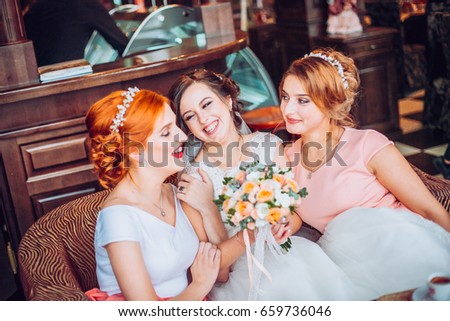 Happy bride and her charming bridesmaids in restaurant terace. Girls with flowers.