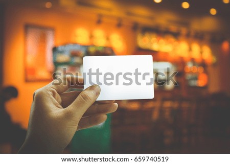 Close up hand holding blank credit card on restaurants background bokeh.