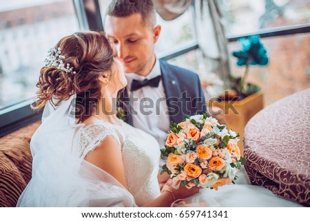Cute married couple in cafe. Bride and groom in interior restaurant kiss each other.